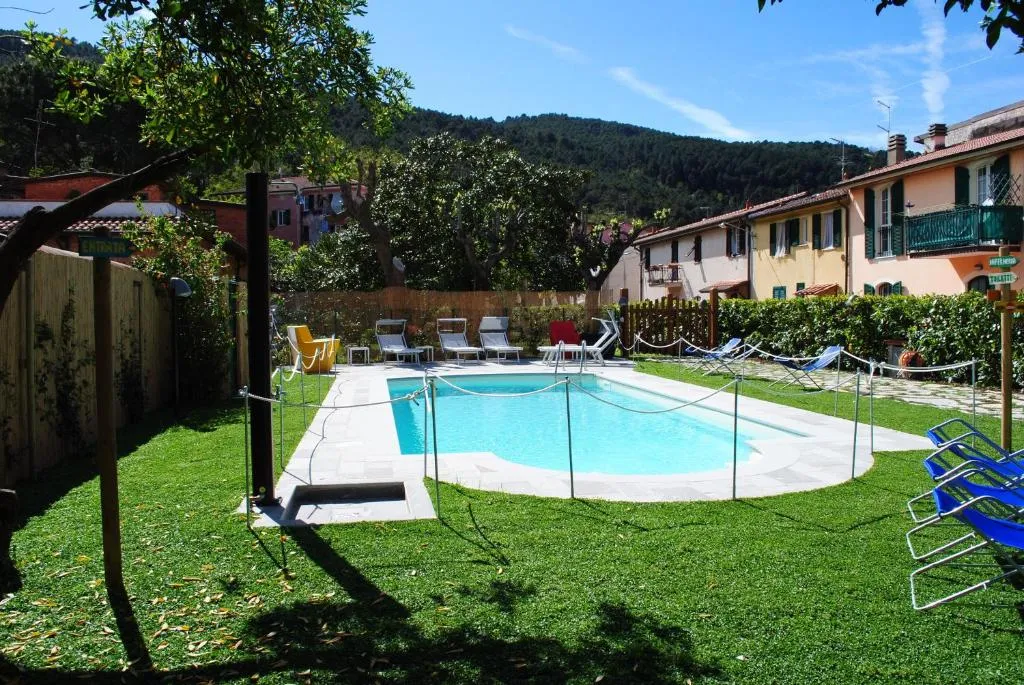 Piscina circondata da prato verde con lettini e vista sulle colline