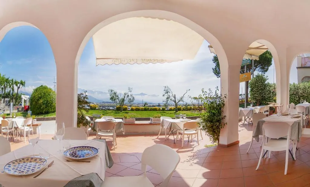 Sala ristorante con archi affacciata sul giardino e vista panoramica sulle montagne