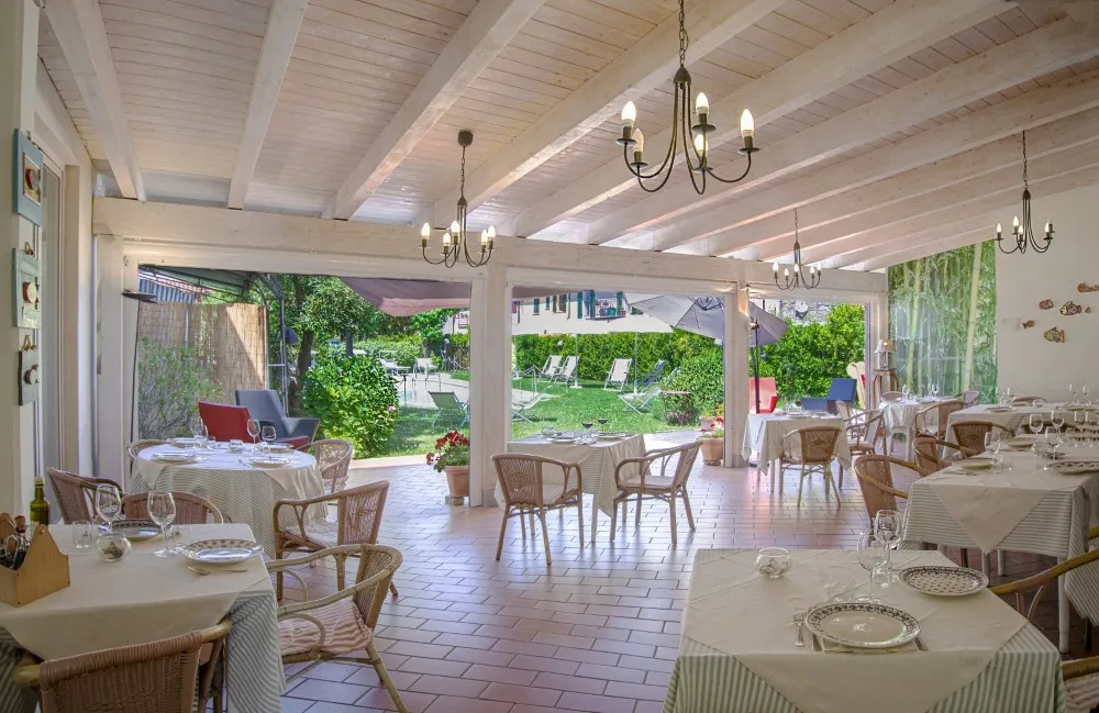 Sala ristorante interna con soffitto in legno, lampadari e tavoli apparecchiati