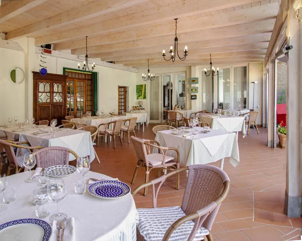 Sala ristorante elegante con tavoli apparecchiati, sedie in vimini e pavimento in cotto