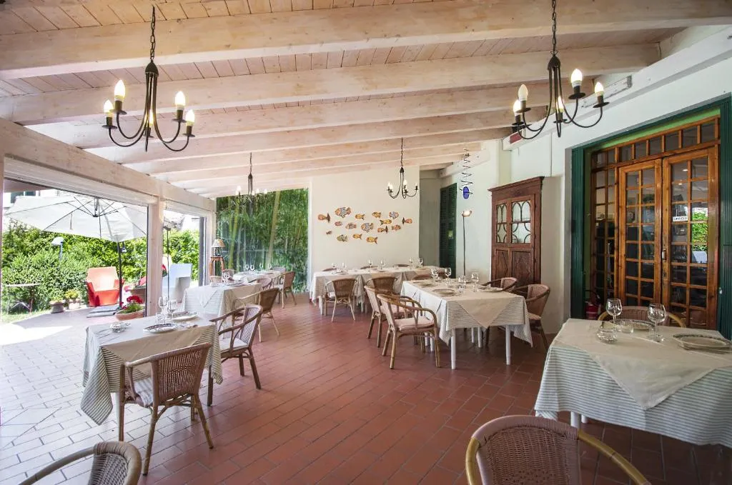Sala ristorante con soffitto in legno e tavoli apparecchiati affacciata sul giardino