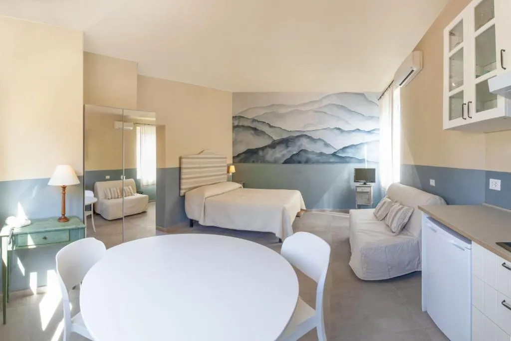 Monolocale con letto, divano, angolo cottura e murale di colline