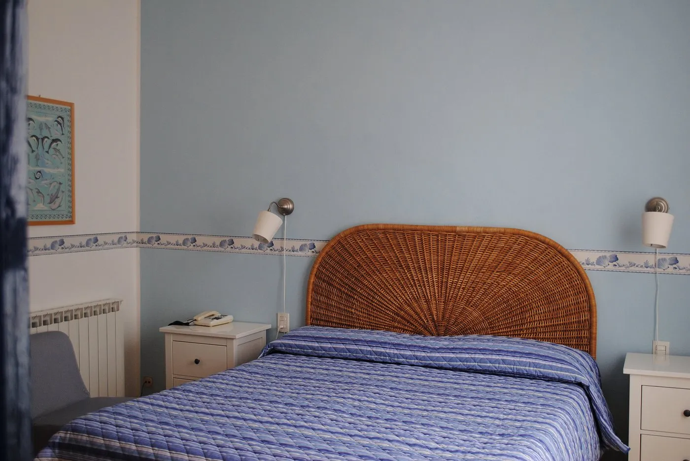 Camera matrimoniale con testiera in vimini e pareti azzurre
