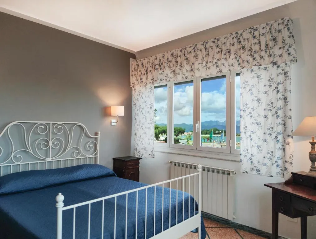 Camera con letto in ferro battuto bianco, copriletto blu e vista sulla laguna