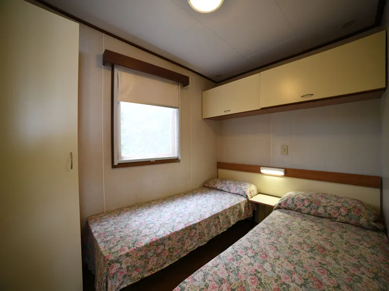 Camera da letto con due letti singoli, copriletto floreale e finestra