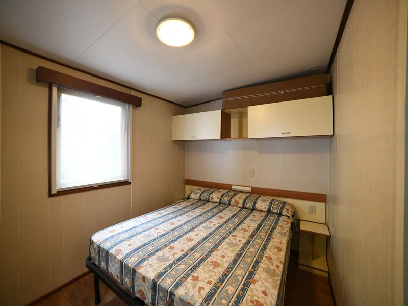 Camera da letto matrimoniale con pareti in legno e pensili