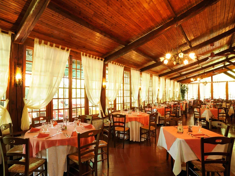 Sala ristorante con soffitto in legno, tavoli apparecchiati e tovaglie arancioni