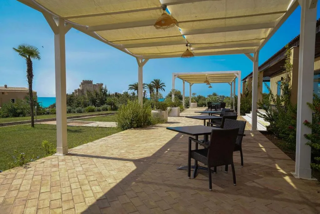 Terrazza coperta con pergola, tavoli e sedie affacciata sul giardino e sul mare