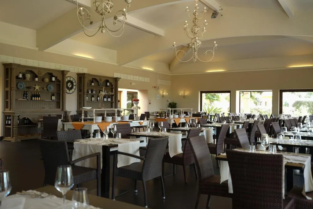Sala ristorante interna con tavoli apparecchiati, lampadari eleganti e grandi finestre