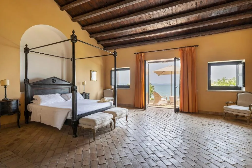 Camera con letto a baldacchino, soffitto in travi di legno e affaccio sul mare