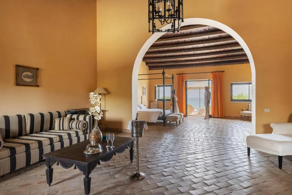 Suite con salotto, divano a righe e camera con letto a baldacchino vista mare