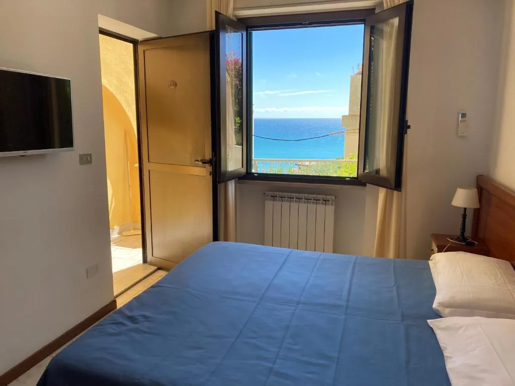 Camera con letto blu, TV a parete e finestra con vista mare