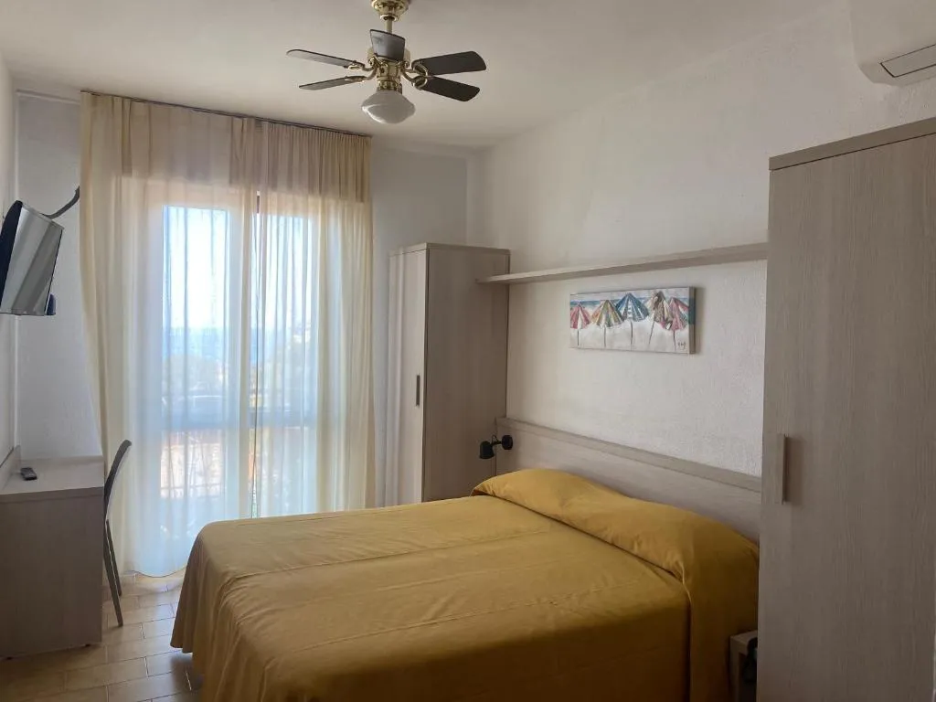 Camera matrimoniale con copriletto giallo, ventilatore a soffitto e finestra luminosa