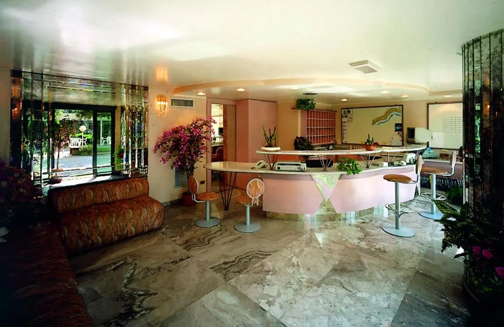 Hall del residence con reception rosa, pavimento in marmo e divano