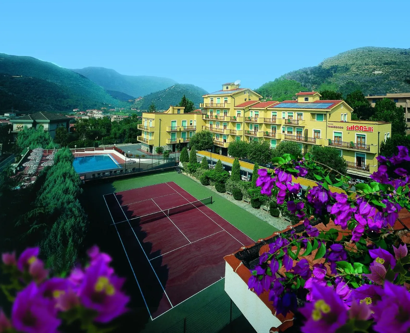 Veduta panoramica del residence con piscina, campo da tennis e colline circostanti