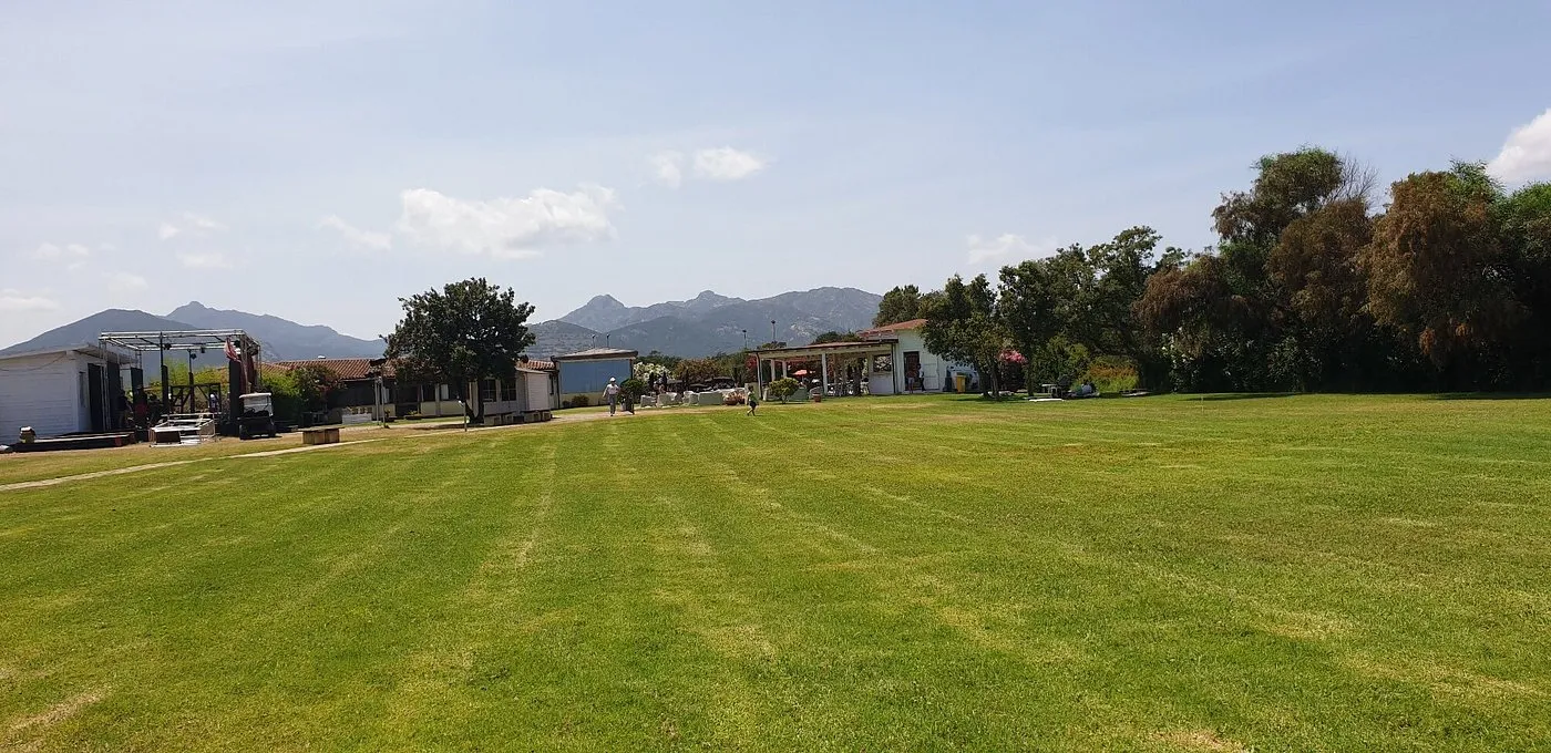Ampio prato verde del villaggio con vista sulle montagne