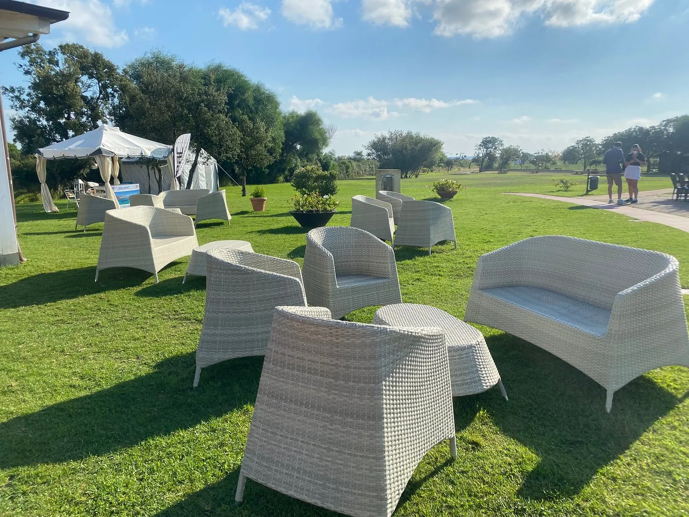 Area lounge esterna con poltrone in rattan su prato verde