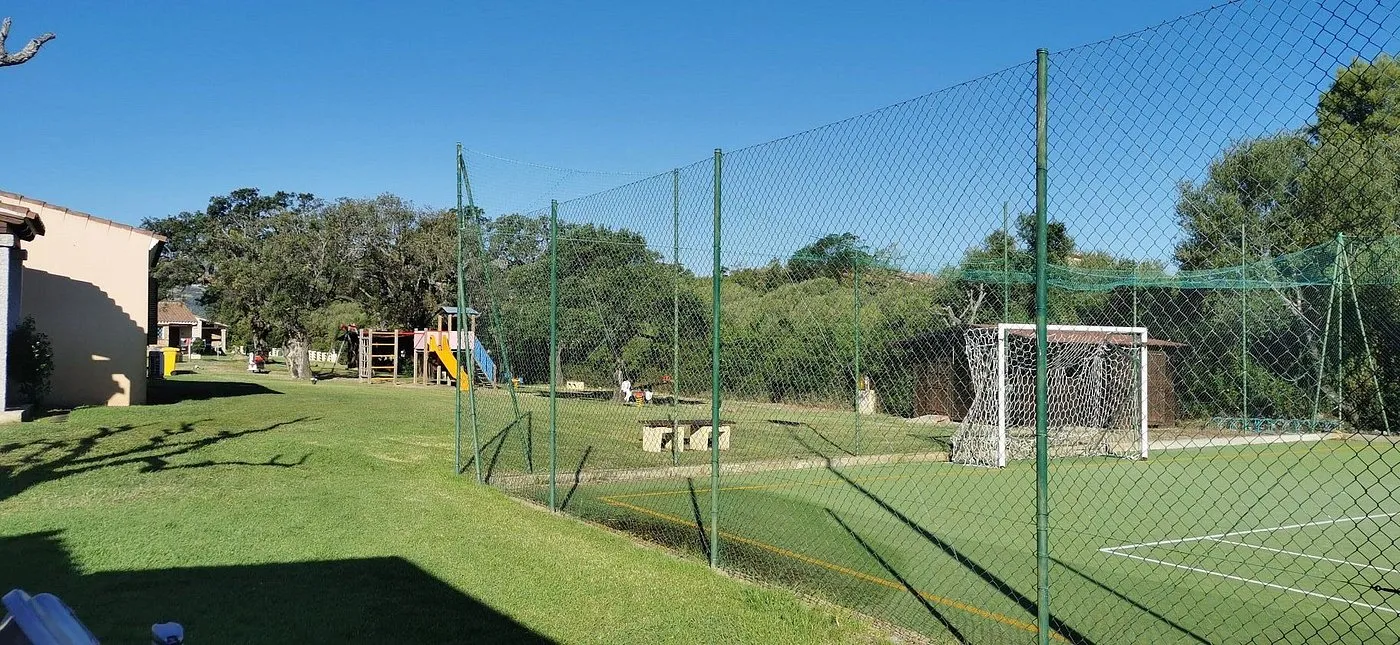 Campo sportivo recintato con parco giochi e area verde