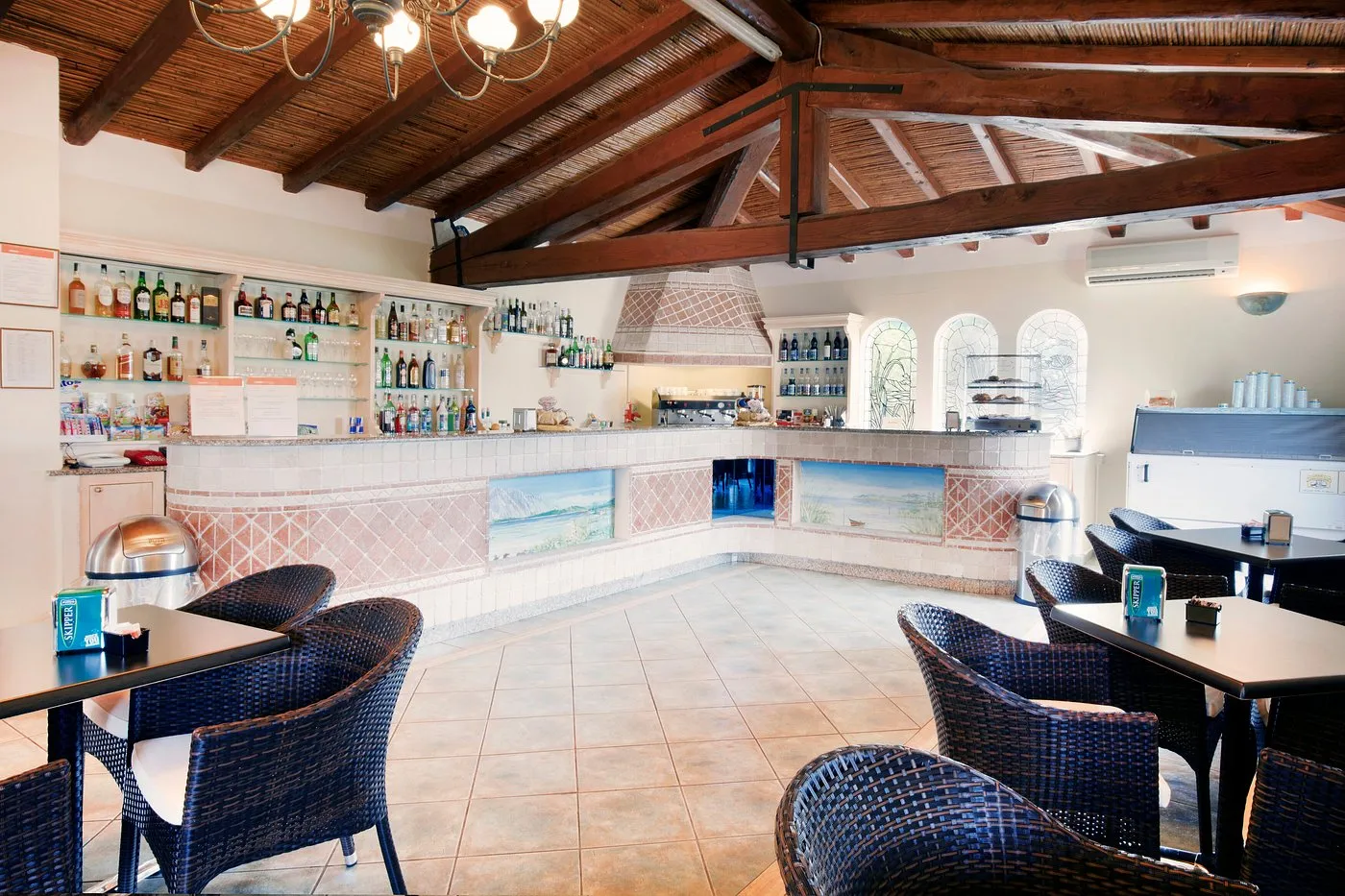 Bar interno con soffitto in legno, bancone piastrellato e tavolini