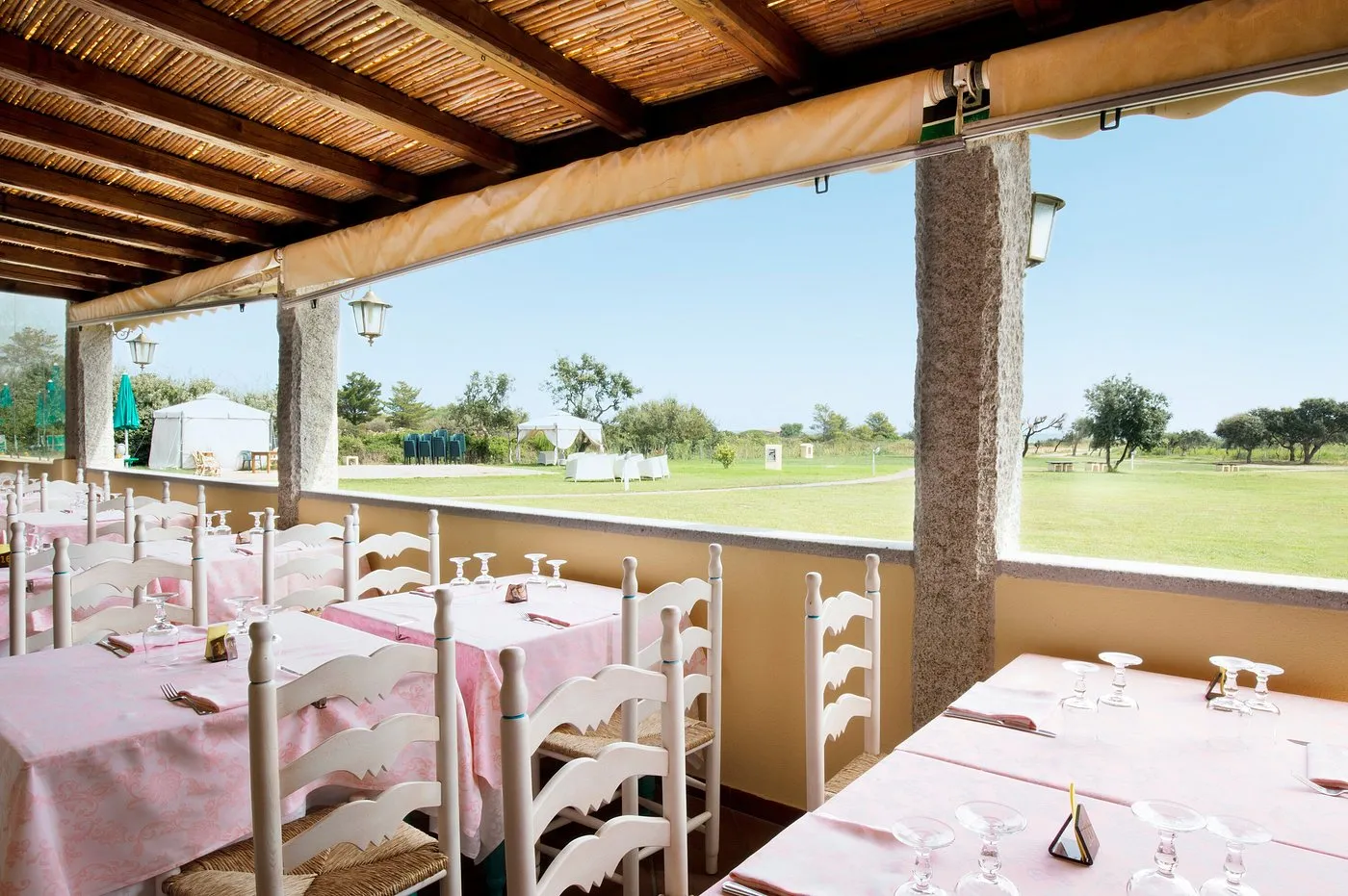 Terrazza ristorante con tavoli apparecchiati e vista sul prato