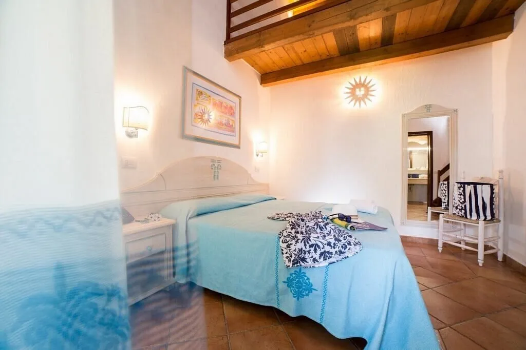 Camera da letto con soppalco in legno e copriletto azzurro
