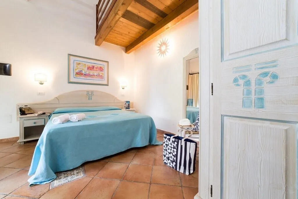 Camera con letto matrimoniale, soffitto in legno e copriletto azzurro