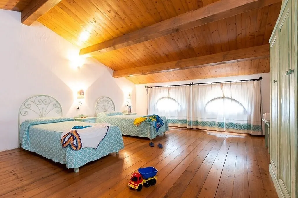 Camera mansardata con due letti singoli e pavimento in legno