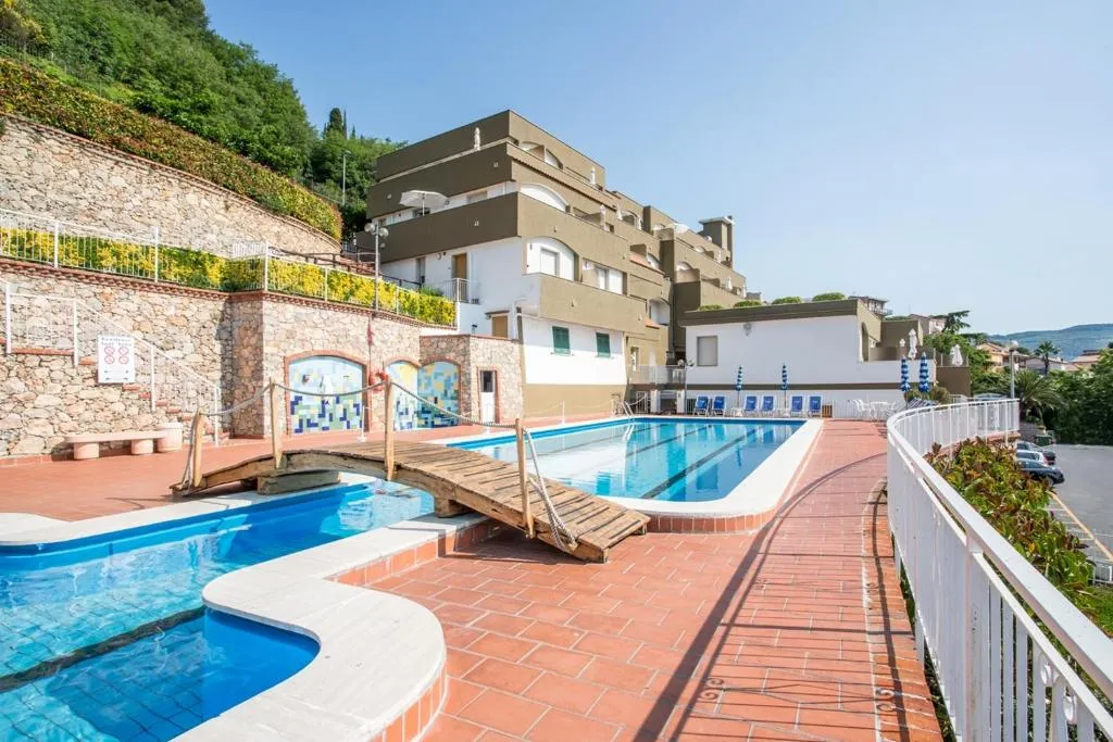 Piscine collegate da ponte in legno con terrazza in cotto e edificio dell'hotel