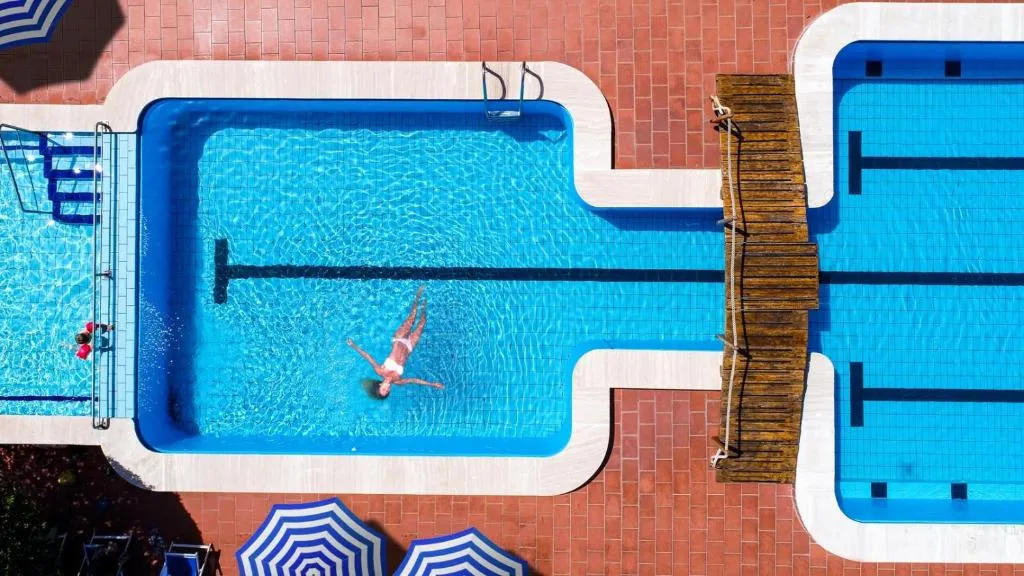 Vista dall'alto di piscina con passerella in legno e persona che nuota