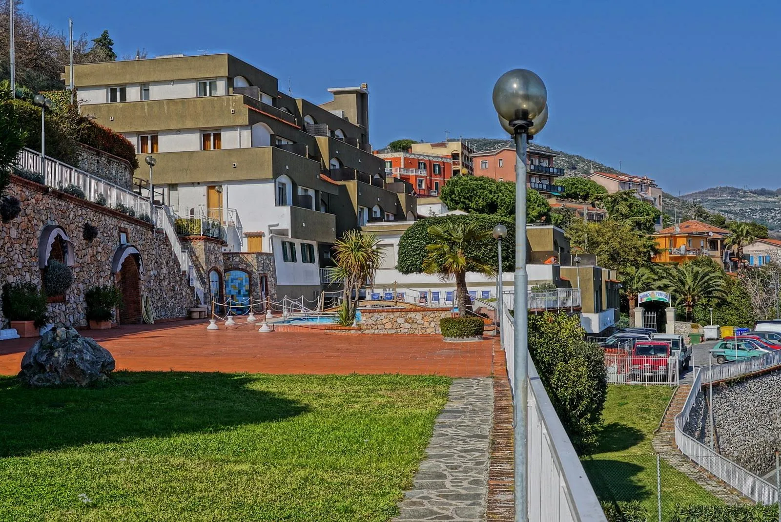 Esterno dell'hotel con edificio in collina, giardino e terrazza in cotto