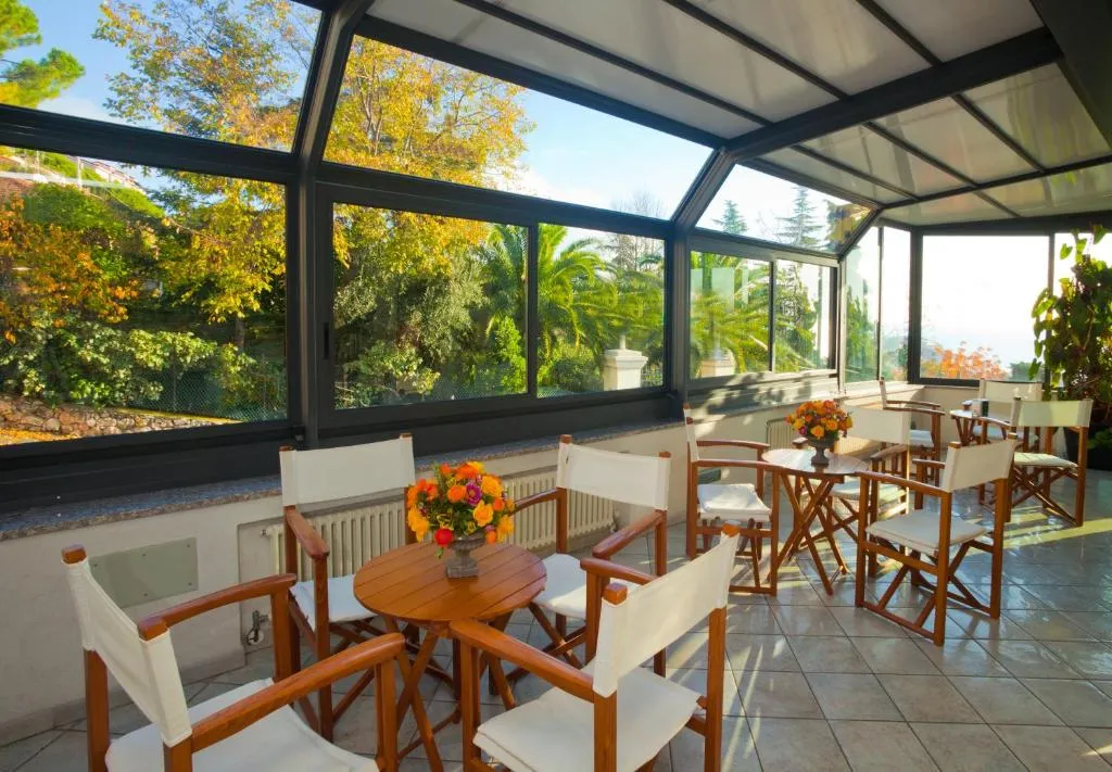 Veranda luminosa con tavoli e sedie in legno e vista sul giardino
