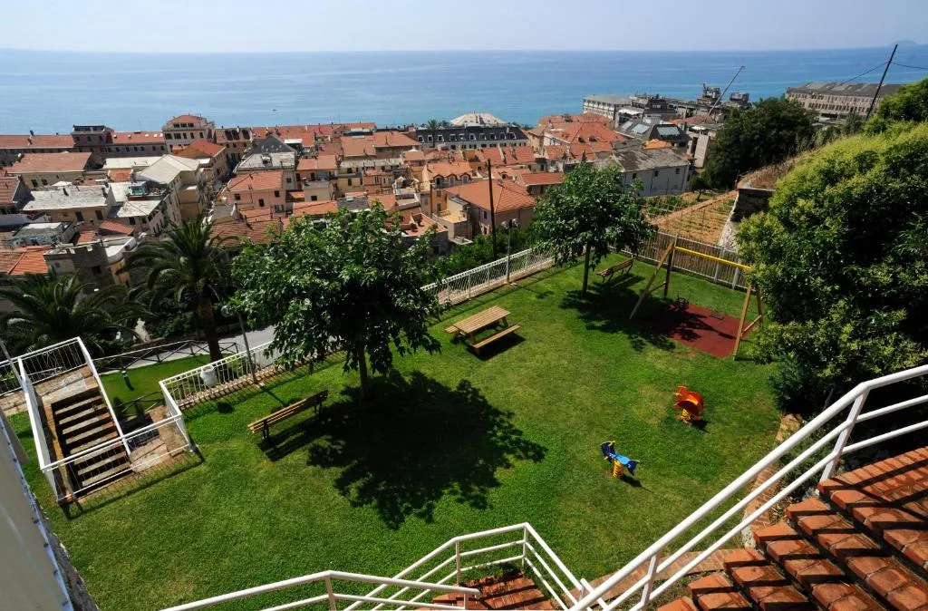 Vista panoramica del giardino con area giochi, tetti del paese e mare