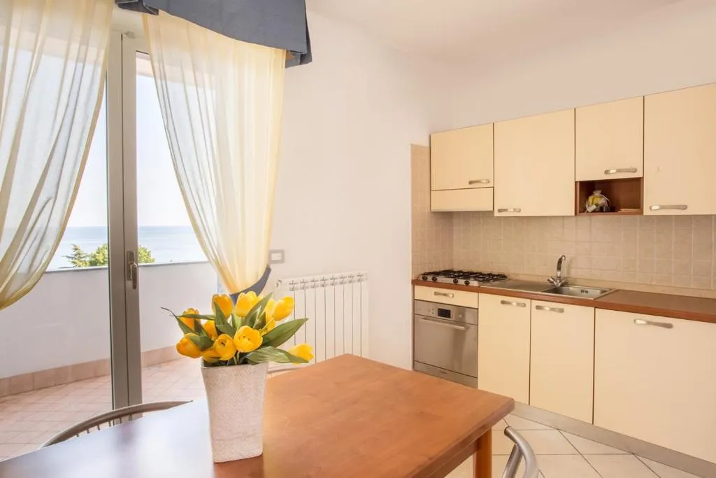 Cucina di appartamento con tavolo, tulipani e vista mare dalla finestra