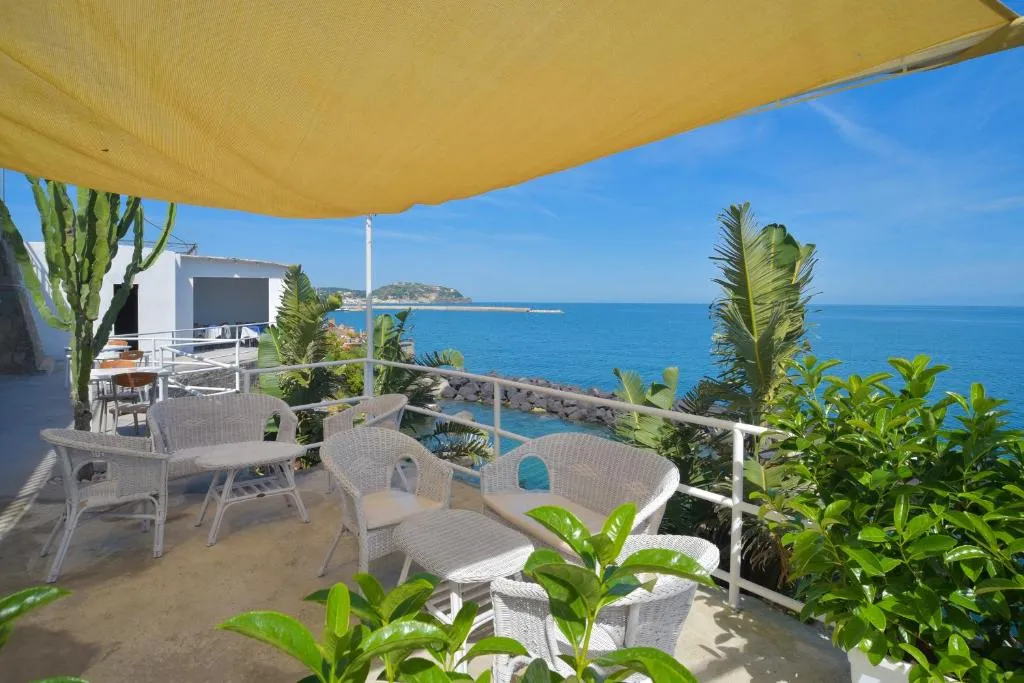 Terrazza con poltrone in vimini e tenda gialla affacciata sul mare