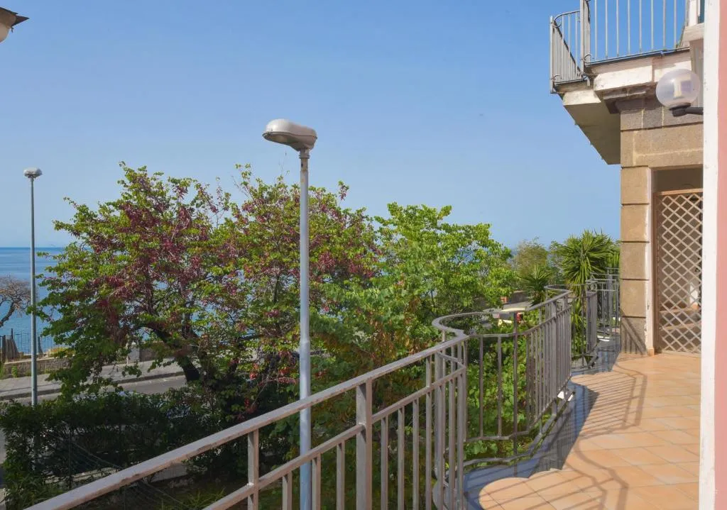 Balcone con ringhiera e vista sul mare tra la vegetazione