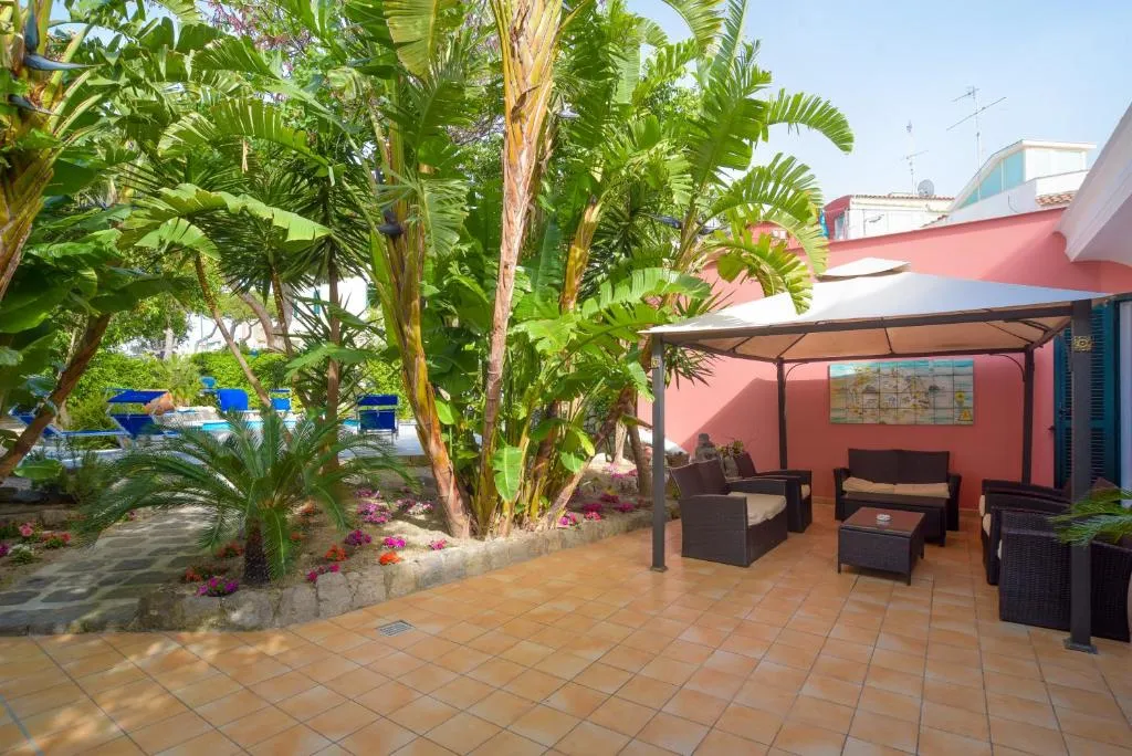 Angolo relax con divani in vimini e gazebo nel giardino tropicale