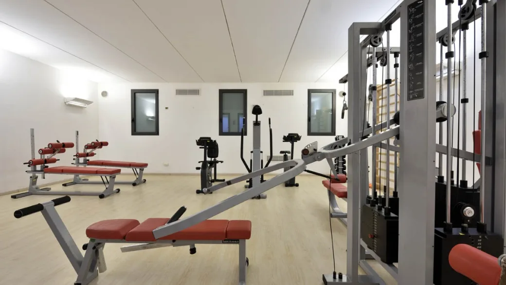 Sala fitness con attrezzi per l'allenamento, panche rosse e macchine isotoniche