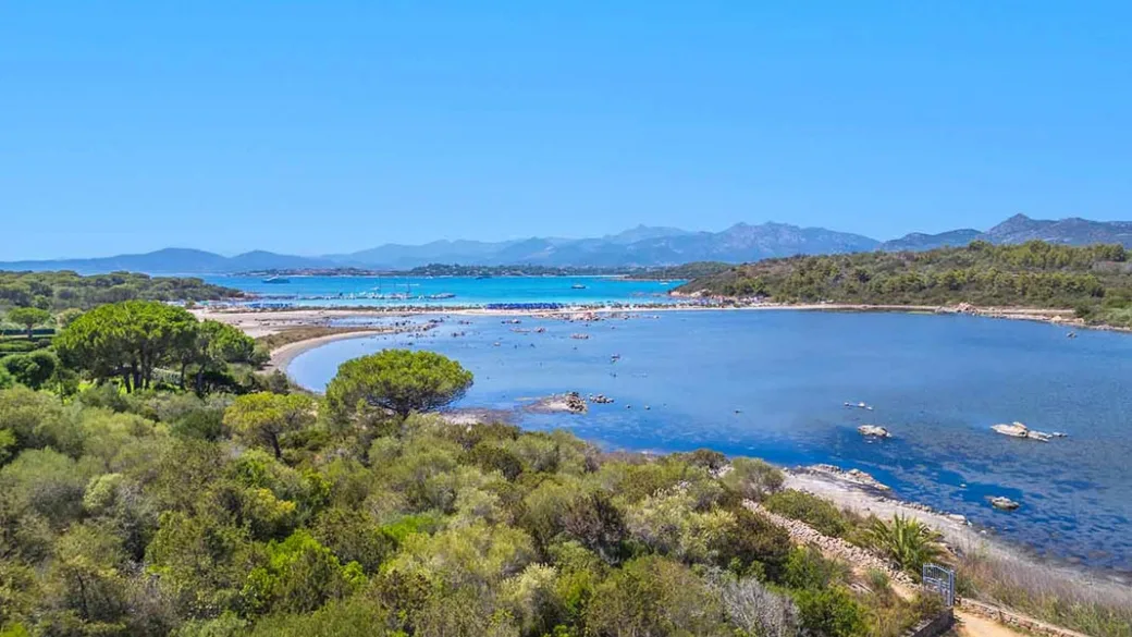 Veduta panoramica di una laguna costiera con vegetazione mediterranea e mare sullo sfondo