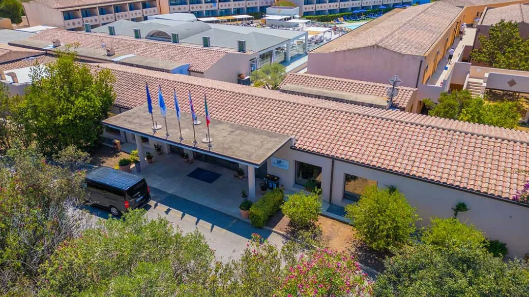 Veduta aerea dell'ingresso del resort con bandiere e area di accoglienza circondata dal verde