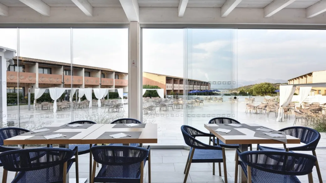 Sala ristorante con tavoli e sedie blu e ampie vetrate affacciate sulla terrazza