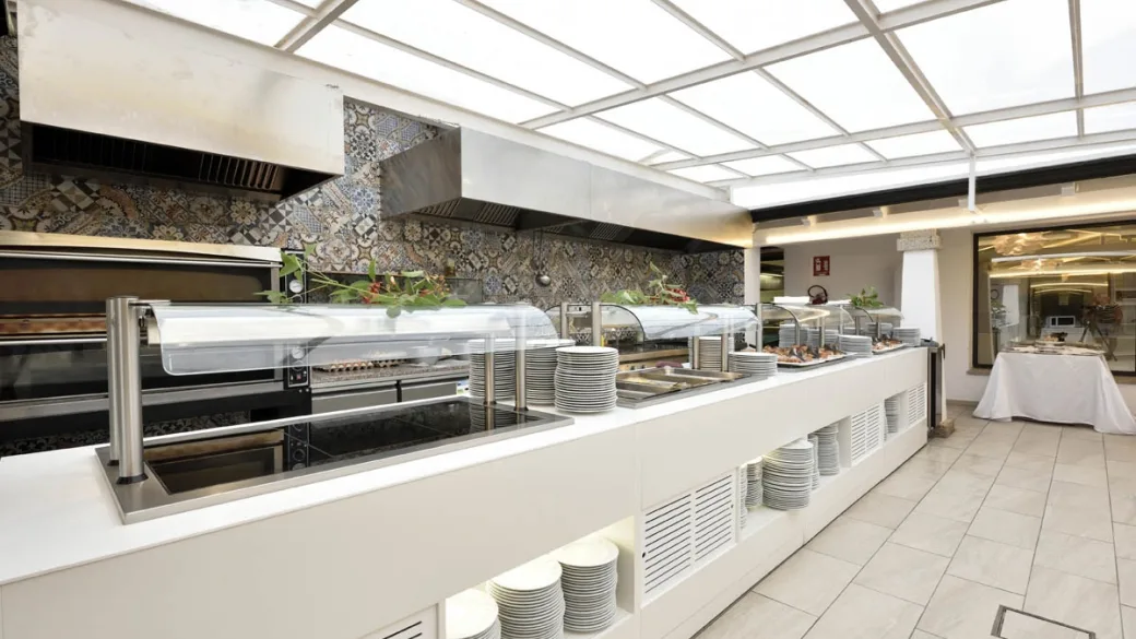 Cucina a vista del ristorante con banco buffet e pareti rivestite di piastrelle decorate