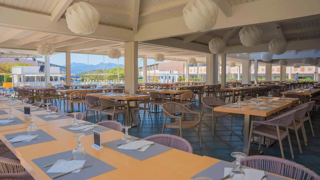 Ampia sala ristorante con tavoli apparecchiati e vista sulle montagne