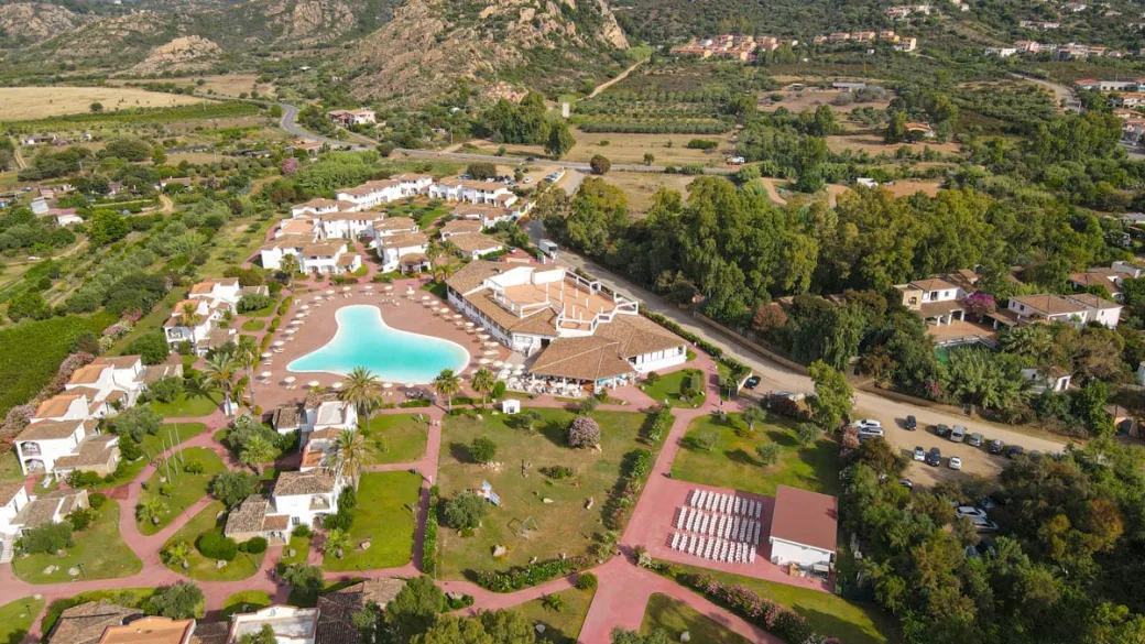 Vista aerea del resort con piscina e giardini circondato da colline