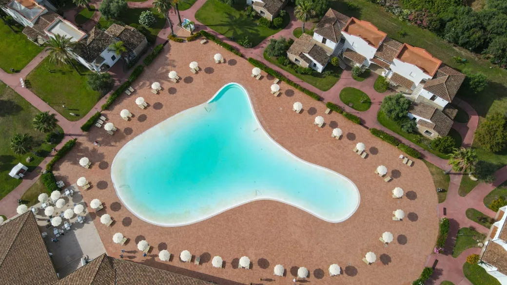 Vista dall'alto della piscina a forma irregolare con ombrelloni bianchi