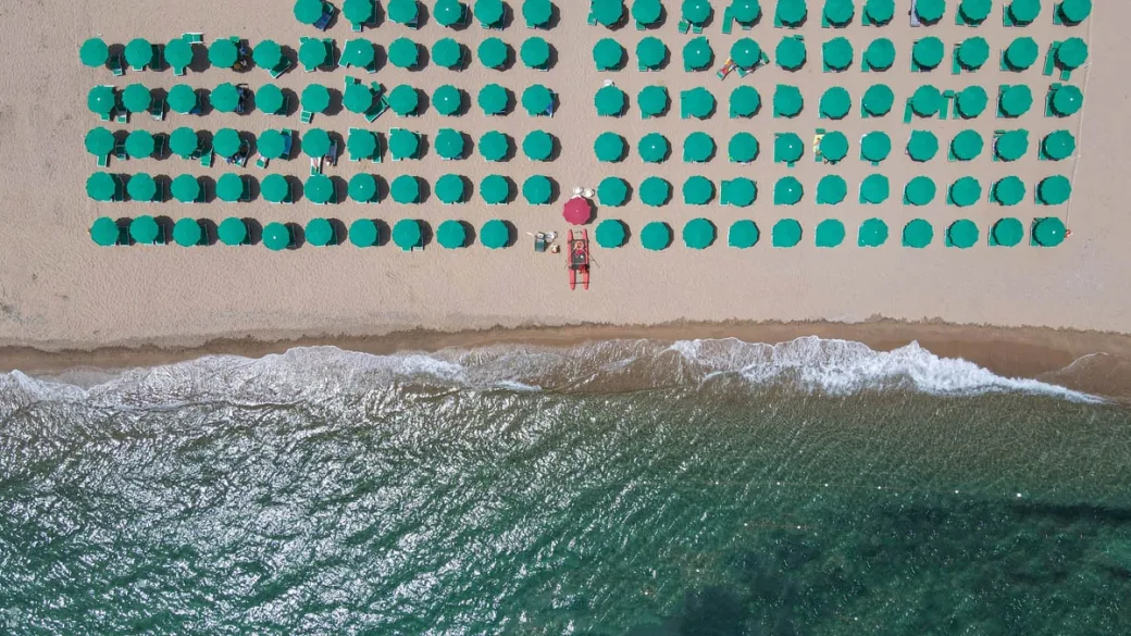 Vista dall'alto degli ombrelloni verdi disposti in fila sulla spiaggia
