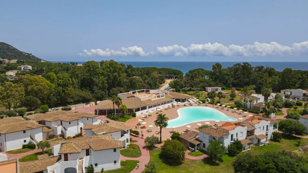 Vista aerea del resort con grande piscina e mare all'orizzonte