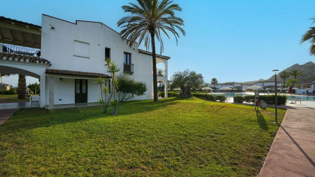 Edificio bianco con palma e vista sulla piscina tra i giardini
