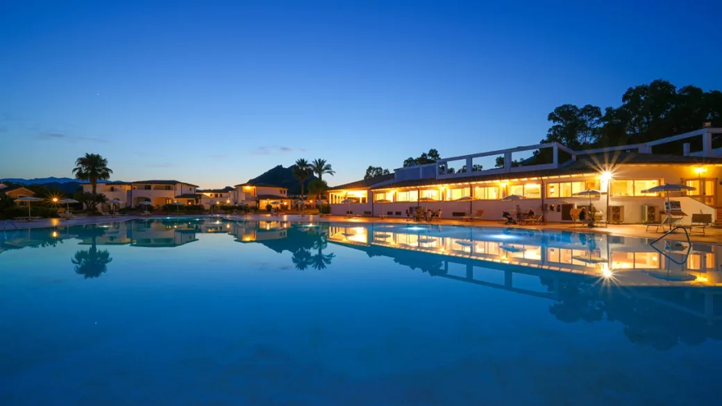 Piscina del resort illuminata al crepuscolo con riflessi sull'acqua