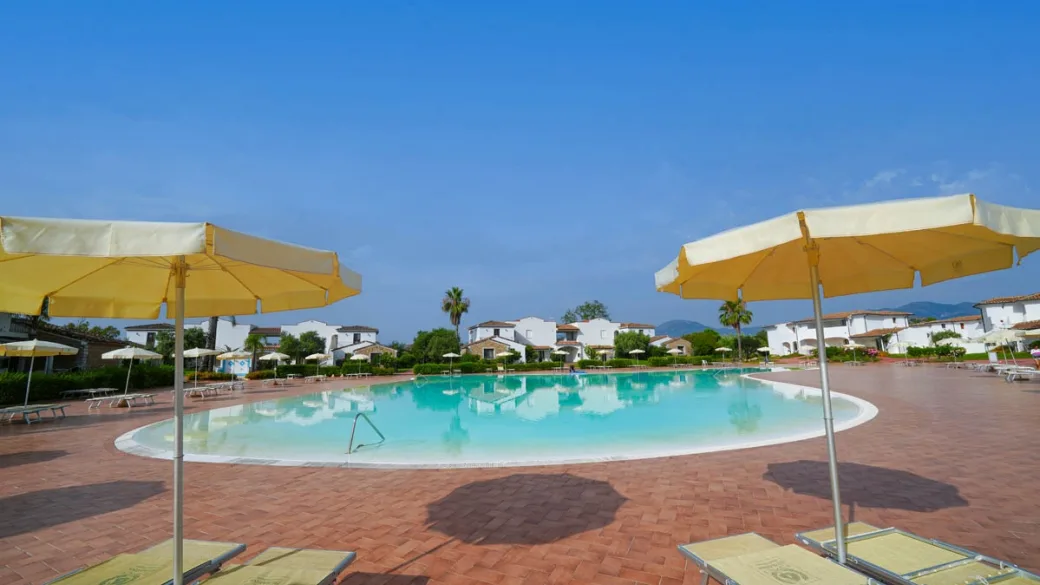Piscina del resort con ombrelloni gialli ed edifici bianchi