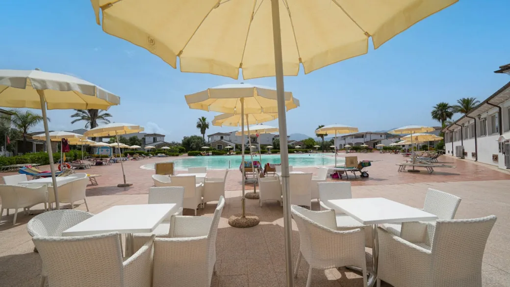 Area bar all'aperto con ombrelloni gialli e tavoli vista piscina